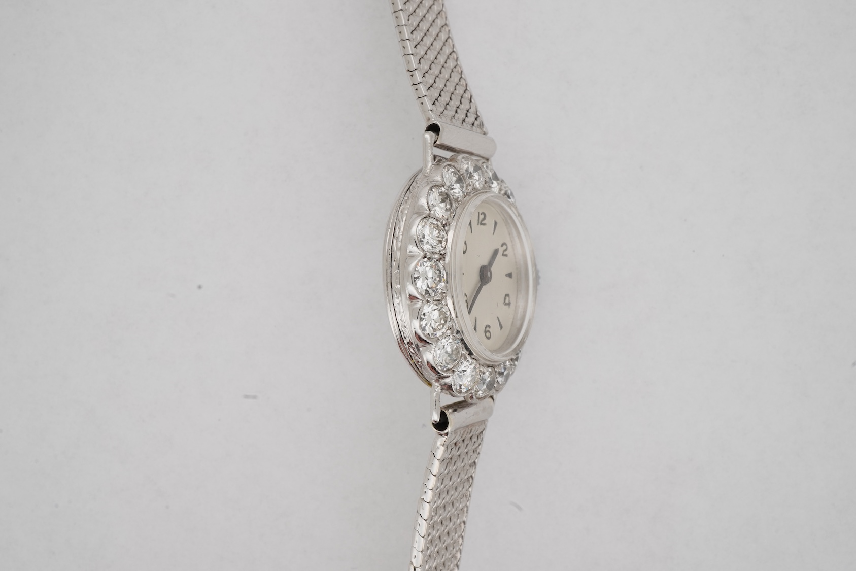 A lady's early 1940's platinum and diamond set manual wind cocktail watch, on a 9ct white gold mesh link bracelet